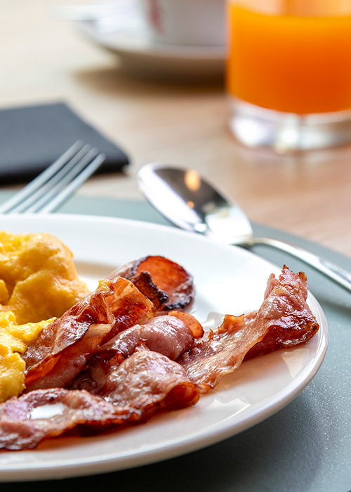 Breakfast at MOOM Hotel with scrambled eggs, crispy bacon and orange juice