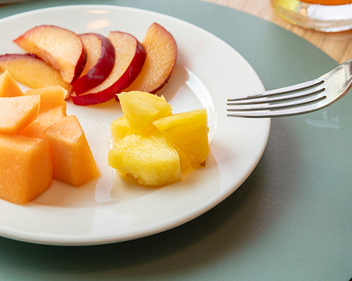Slices of peach, pineapple cubes and fresh melon served on a plate