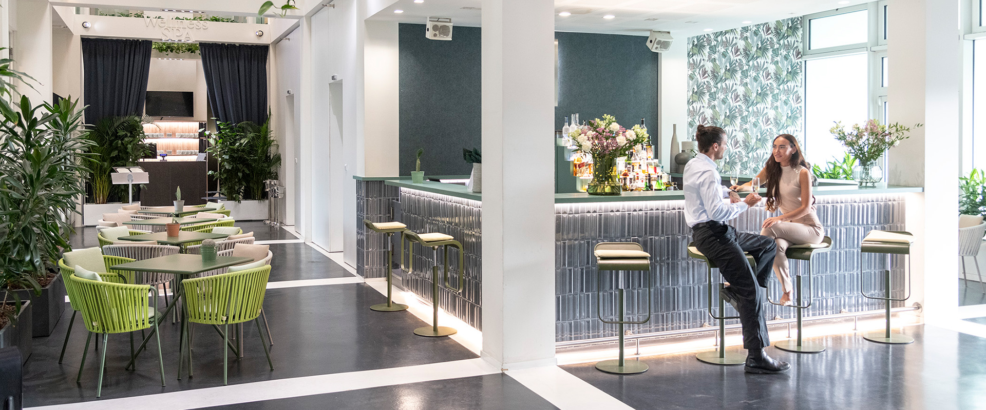 Bar elegante all’ingresso dell’hotel con decorazioni floreali e colori moderni e accoglienti