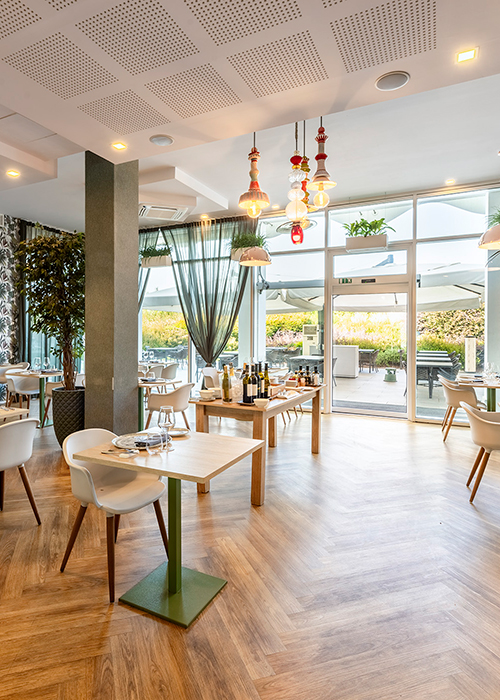 Tavoli del Lounge Bar esterno sotto ampi ombrelloni bianchi con vista sul verde
