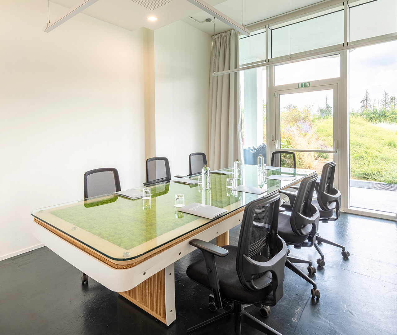 Sala Stampa con tavolo di design in muschio, sedute eleganti e schermo per presentazioni