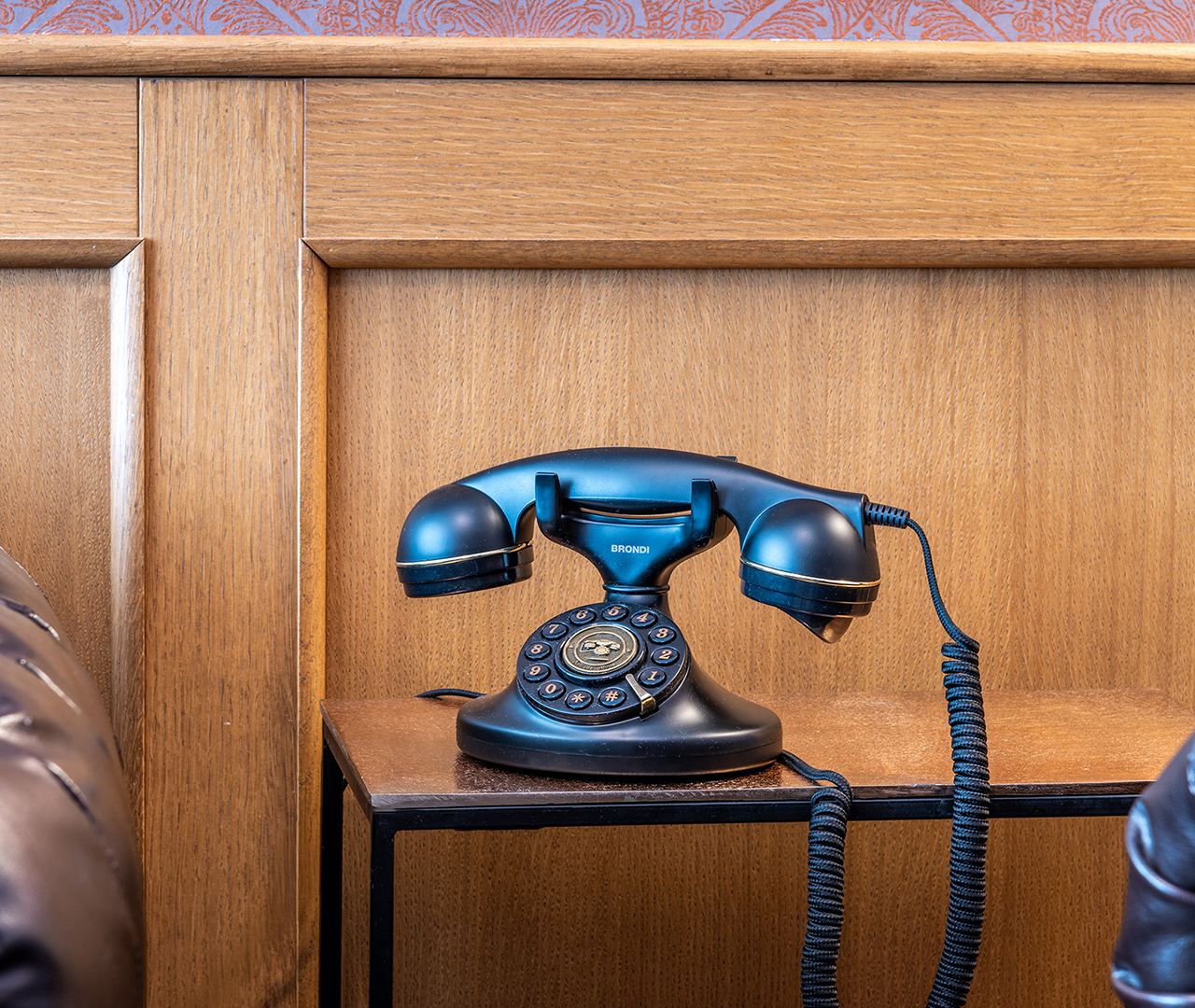 Telefono vintage blu scuro su tavolino in legno nella sala sigari.