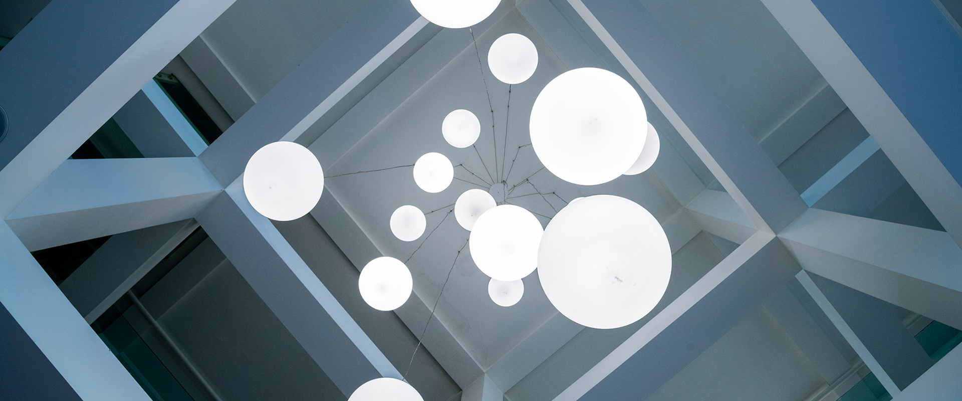 Dettaglio architettonico del soffitto della lobby con moderne lampade sferiche e travi a vista