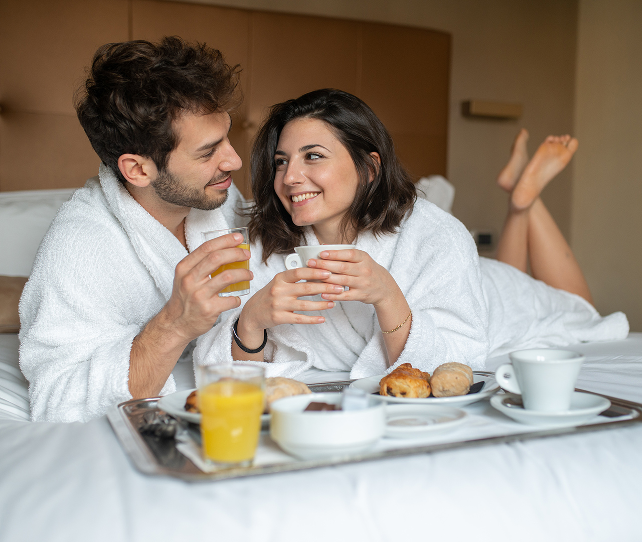 Ospiti in accappatoio si rilassano a letto con il vassoio della colazione del nostro servizio in camera
