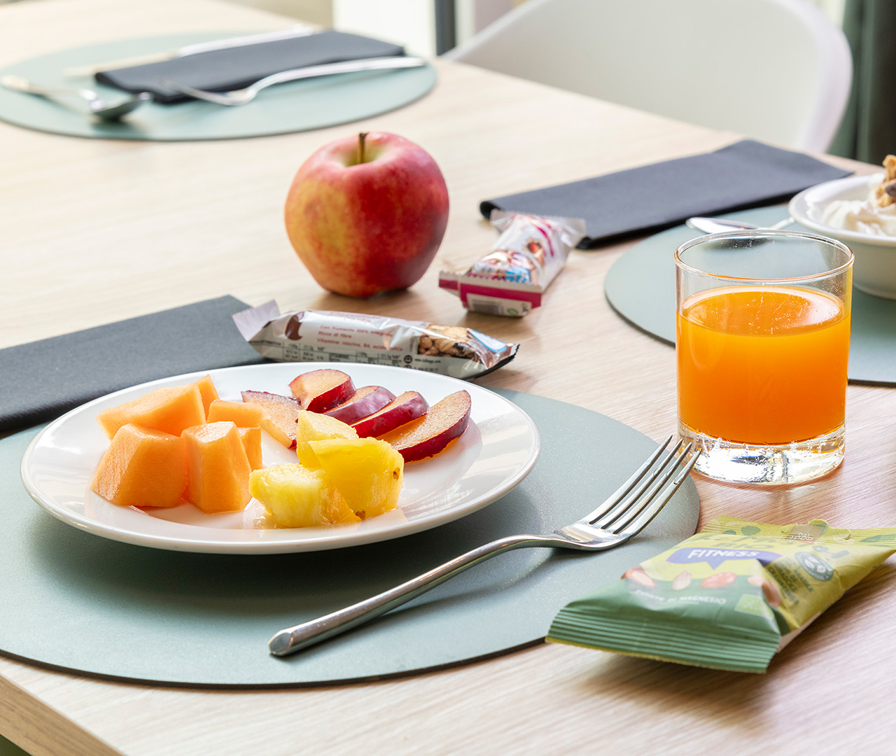 Una proposta di colazione sana e leggera, con frutta di stagione tagliata, una mela e spremuta d'arancia