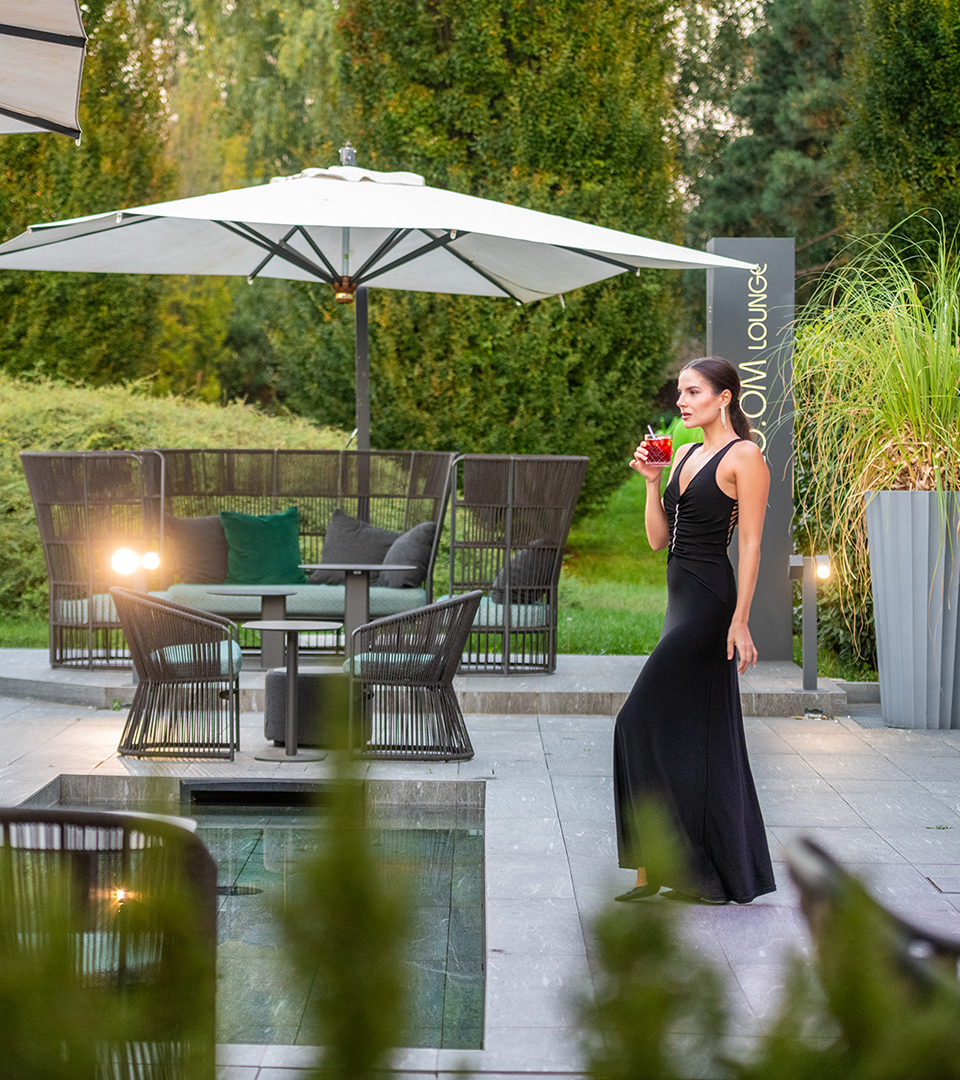 Area esterna del lounge bar del Moom Hotel con eleganti arredi da giardino, ombrelloni e tavolini a bordo piscina
