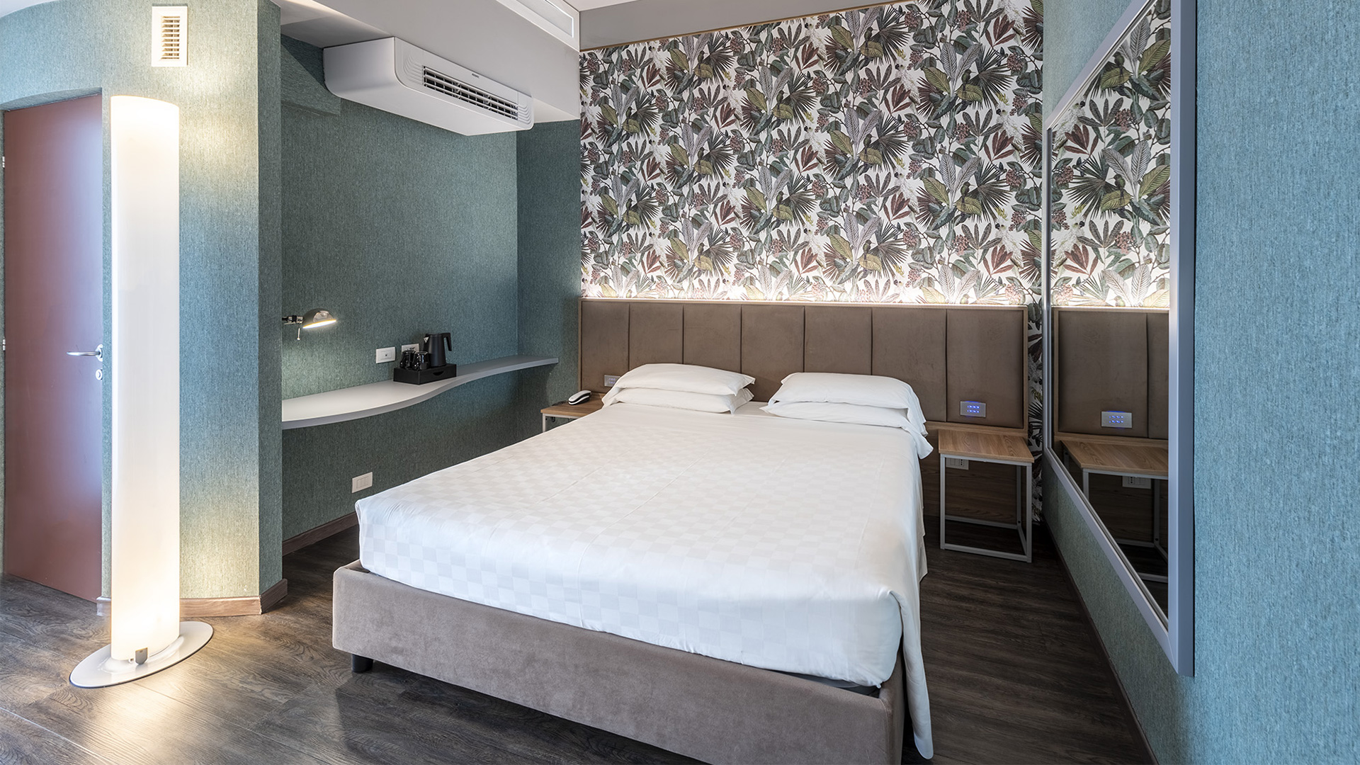 Camera Deluxe con letto matrimoniale, testiera imbottita, parete con carta da parati floreale retroilluminata, scrivania sospesa e grande specchio a parete