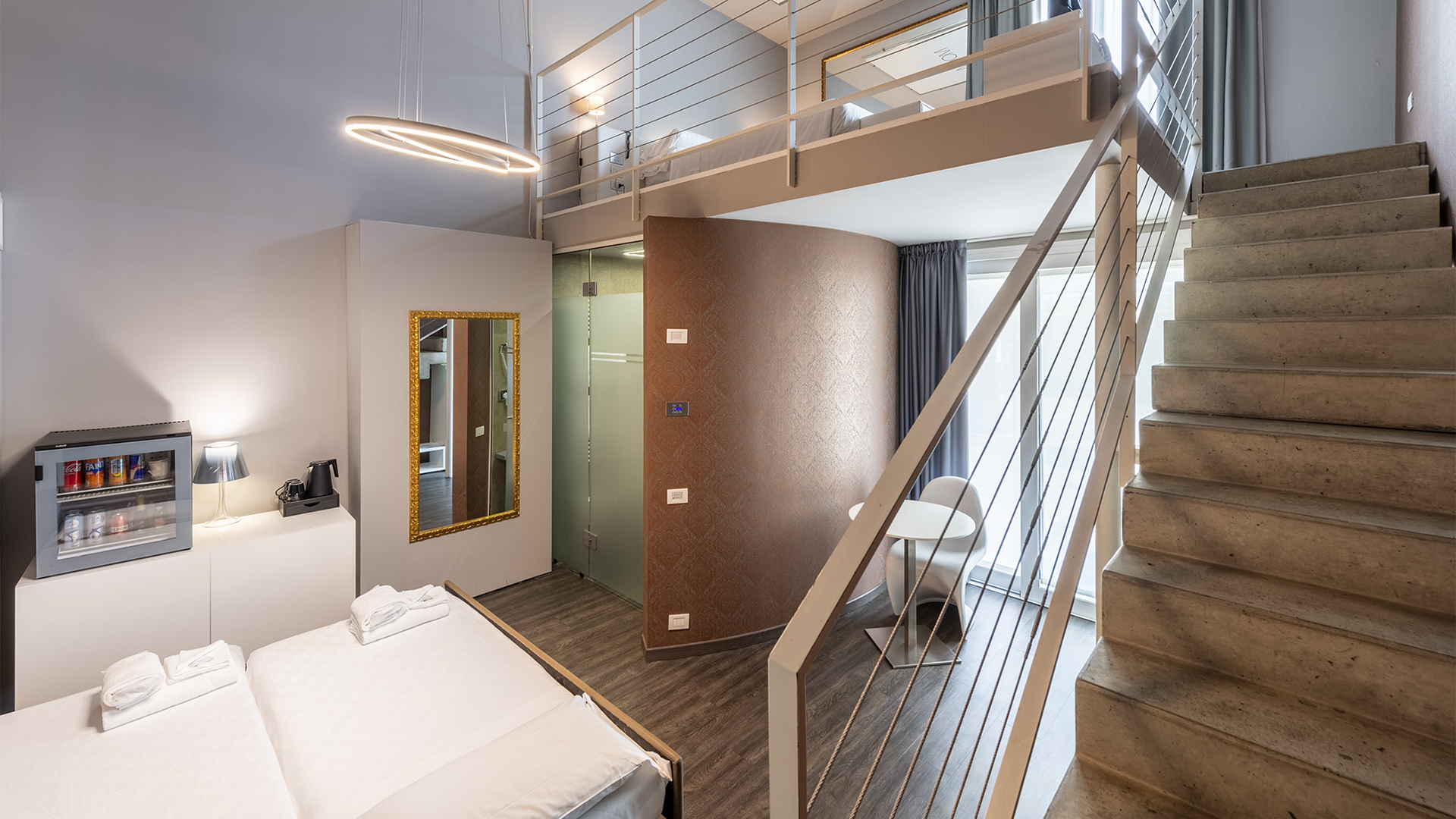 Moderna suite familiare su due livelli, con open space, pareti grigie e pavimento in legno scuro