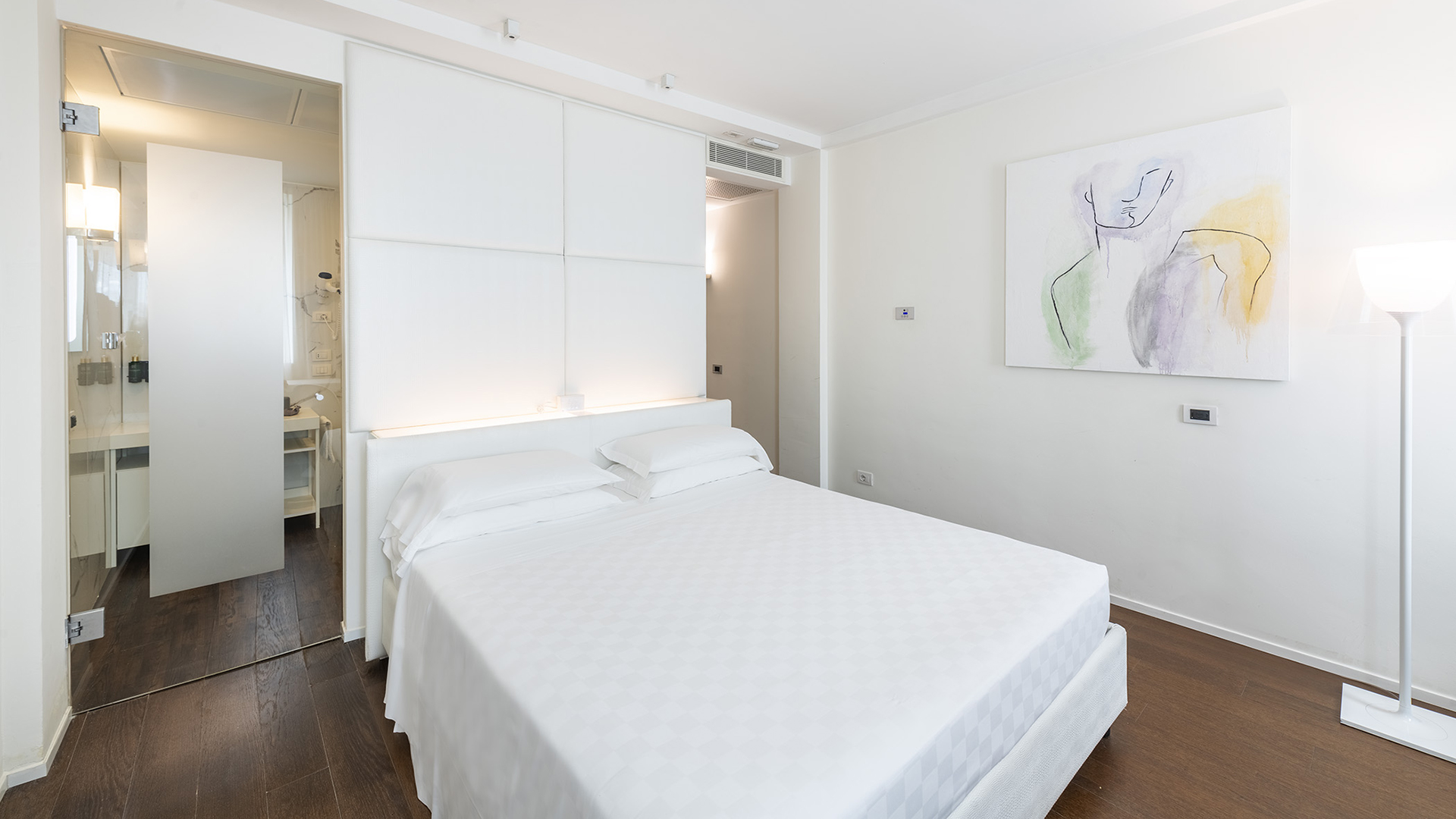 Serena camera superior con letto matrimoniale, lenzuola candide, pareti bianche e un moderno bagno