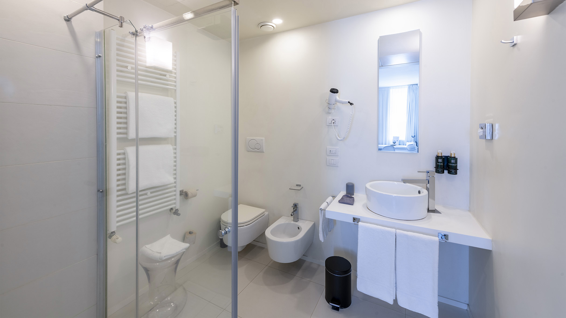 Bagno elegante e sereno di una camera Superior, con pareti bianche, piastrelle beige chiaro e illuminazione chiara